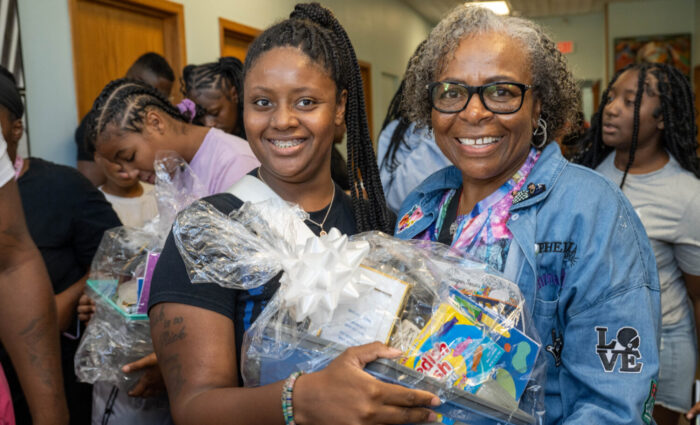 Picture of Dorothy McCollum (person on the right) giving out a supply basket to a person.